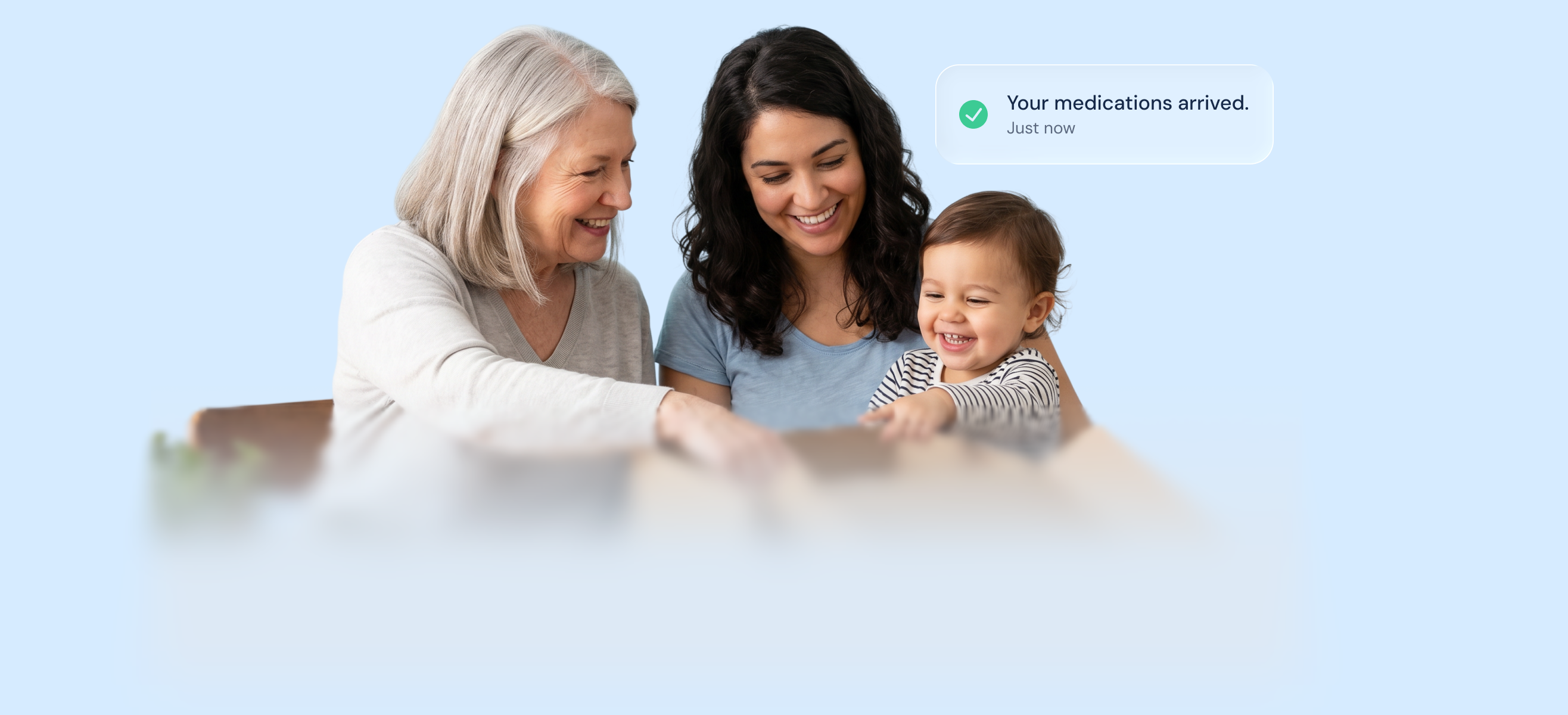 Three generations &mdash; grandmother, mother and baby &mdash; sharing a moment, with a notification confirming &lsquo;Your medications arrived&rsquo;
