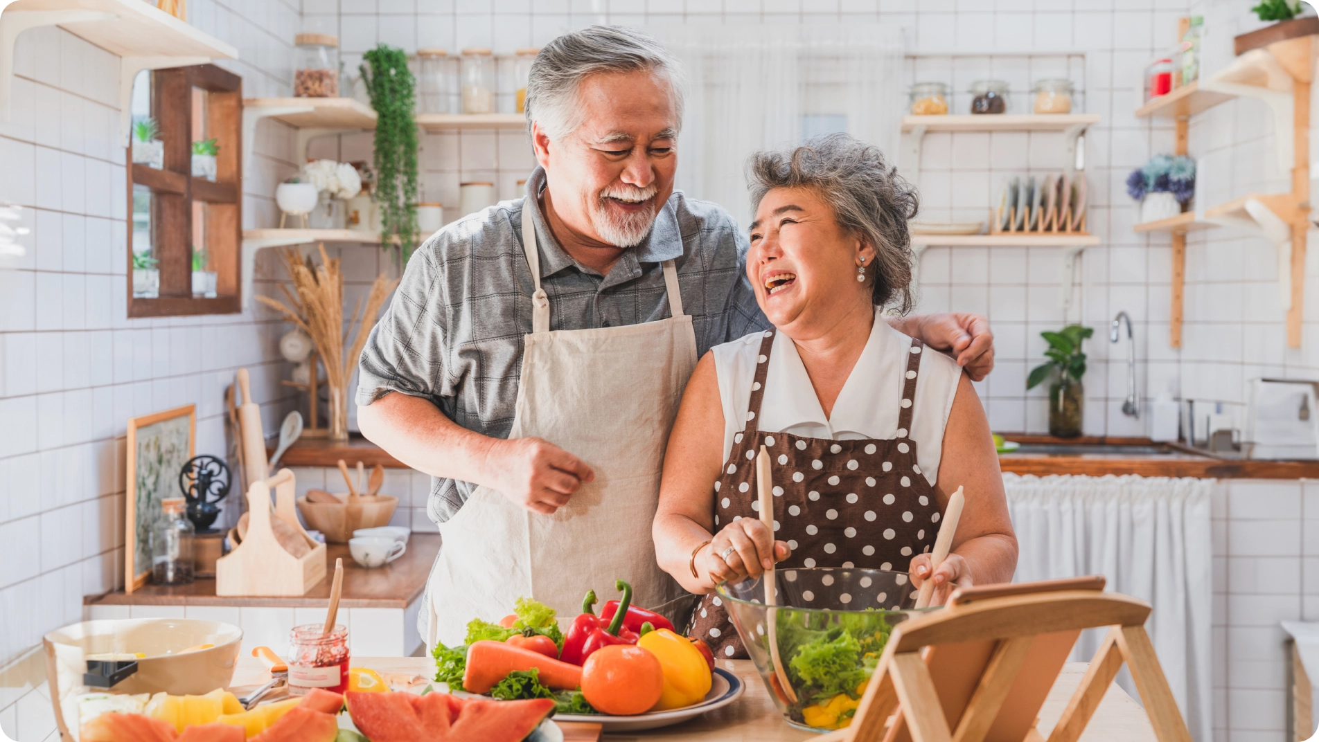 Older couple laughing in kitchen cooking a Mediterranean Diet